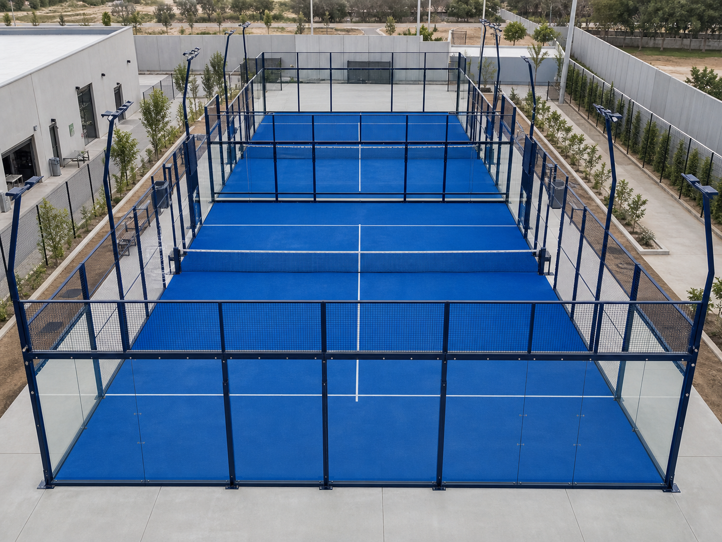 Standard framed padel court with glass panels, mesh enclosure, blue turf and lighting.